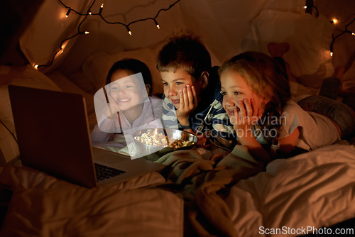 Image of Children, computer and watch in tent at night with movies, film or cartoons for holiday adventure or vacation. Young boy, girl or kids with lights, pillows and blanket at home on laptop for Netflix