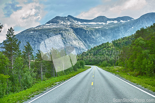 Image of Mountain, road trip and forest highway with travel, holiday and countryside scenery in Norway. Nature, clouds in sky and street for journey, vacation and outdoor adventure with woods, trees and snow