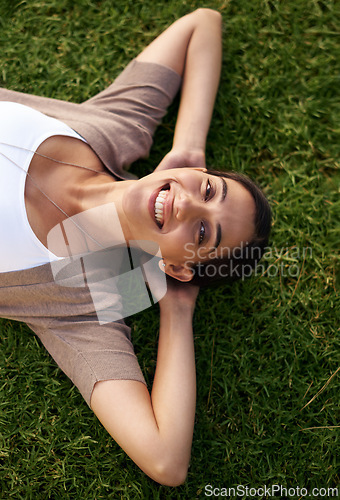 Image of Woman, relax and lying on grass while resting, above and enjoy summer or nature outdoor. Female person, smile and sunshine after holiday or vacation, calm lady and happiness in park or outside