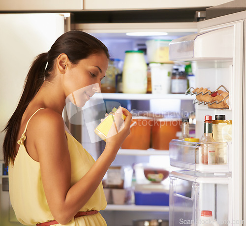 Image of Fridge, cooking and woman with sauce in kitchen checking nutrition label for preparing meal. Food, ingredients and female person reading information on mustard for dinner, supper or lunch at home.