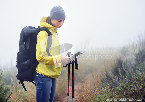 Image of Woman, hiker and reading map on trail in nature, fog and guide for direction on mountain path. Sports gear in bag for supplies, adventure or fitness with natural winter for health in winter peace