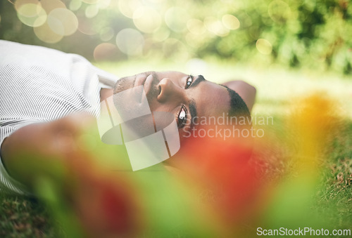 Image of Man, portrait and lying on grass while resting, smile and enjoy summer or outdoor. Black person, relax and sunshine after holiday or vacation, comfortable and happiness in park or nature flare