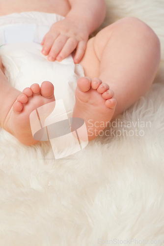 Image of Baby feet, cute and toes in bedroom, blanket and playtime in diaper for child development in skin care. Infant, kid and wellness for newborn, adorable and rug in house for home and toddler fun