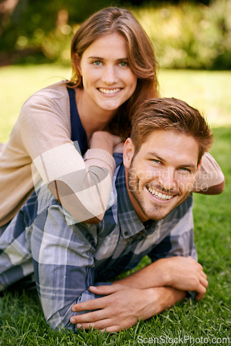 Image of Couple, park and grass with smile, portrait and love for date and relationship or bonding. Man, woman and nature with romance, new york and sunshine lying together on outdoor adventure or holiday