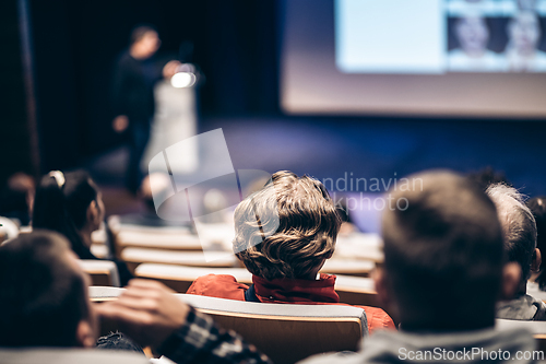 Image of Speaker giving a talk in conference hall at business event. Rear view of unrecognizable people in audience at the conference hall. Business and entrepreneurship concept.