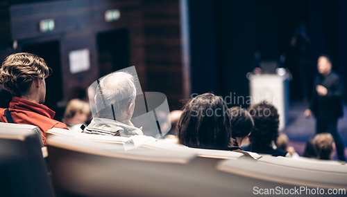 Image of Speaker giving a talk in conference hall at business event. Rear view of unrecognizable people in audience at the conference hall. Business and entrepreneurship concept.