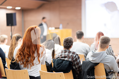 Image of Speaker giving a talk in conference hall at business event. Rear view of unrecognizable people in audience at the conference hall. Business and entrepreneurship concept.