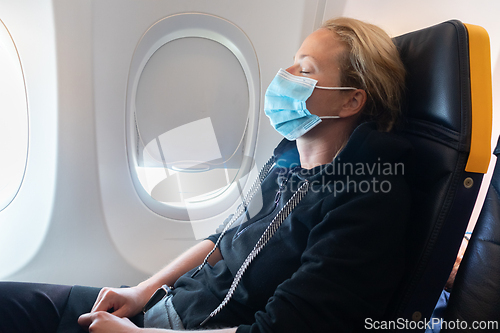Image of A young woman wearing face mask is traveling on airplane , New normal travel after covid-19 pandemic concept.