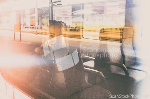 Image of Woman traveler contemplating outdoor view from window of train. Young lady on commute travel to work sitting in bus or train.