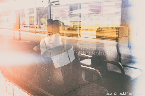 Image of Woman traveler contemplating outdoor view from window of train. Young lady on commute travel to work sitting in bus or train.