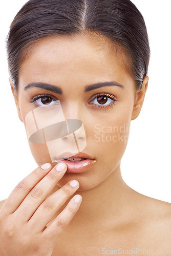 Image of Girl, serious and dermatology for skincare in studio as model in white background for woman. Female person, beauty and hand on her lips with lipgloss from cosmetics for self care and brunette hair