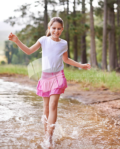 Image of Little girl, smile and countryside in stream with happiness, feet and game of walking. Child, cute and playing in nature with joy, carefree and freedom on warm summer, water splash and energy