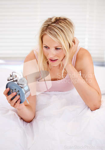 Image of Woman, alarm clock and lazy for waking up in bed, tired and sleepless or fatigue at home. Female person, exhausted and pressing or hit snooze in apartment, frustrated and annoyed or late and anxious