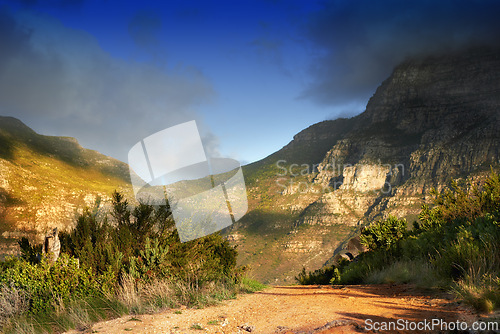 Image of Mountains, nature and clouds in sky for travel, hiking and eco friendly tourism with dirt road, path or trail. Background of environment, landscape and bush in summer for biodiversity in Cape Town