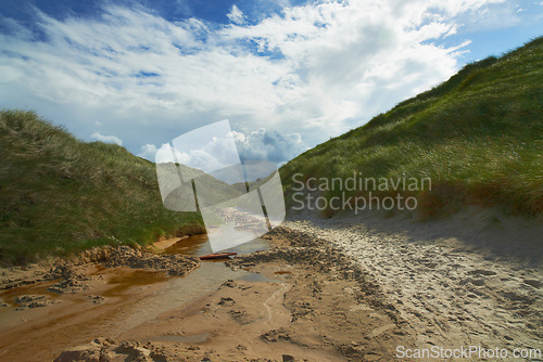 Image of River, nature and landscape of water stream, green hill and beach with texture and mud in environment for ecosystem. Moving liquid, sea or lake with natural resource, element and landscape outdoor