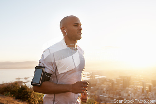 Image of Man, running and sunset with earphones on mountain for workout, exercise or cardio training. Active male person or runner listening to music, podcast or audio for motivation in health and wellness