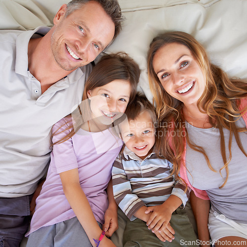 Image of Love, portrait and happy family in bed for relax on holiday, vacation or hotel accommodation on weekend. Face, parents and children with smile, bonding and above in bedroom with healthy relationship