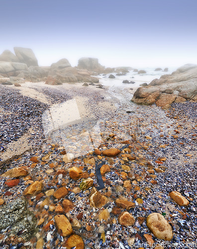 Image of Beach, rocks and stone on sand in nature, landscape or environment with fog on sea or horizon. Offshore, ocean and travel on vacation or holiday to South Africa in summer to calm water or waves