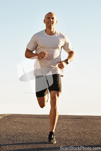 Image of Man, running in street and fitness for cardio, health and fresh air when training for marathon with sky background. Sports, exercise and athlete in portrait for workout, wellness and endurance