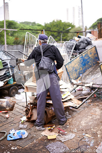 Image of Man, worker and recycling of garbage for waste management in city with rear view, bag and scrapyard. Person, back and search by dumpster site for scrap, rubbish and trash in neighborhood for litter