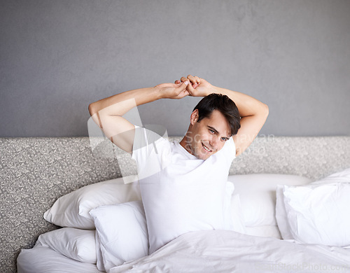 Image of Man, home and stretch in bed, adult and smile for daily routine and rest and wellness. Male person, happy and bedroom in sleepwear and morning for waking up and relaxing on Saturday day off.