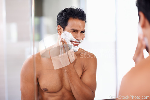 Image of Man, skincare and foam on face in bathroom mirror for shaving, grooming and hair removal. Smile, cosmetics and happy male person for wellness, facial treatment or morning routine with reflection.