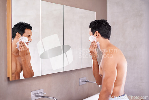 Image of Skincare, mirror and man with foam on face in bathroom for shaving, grooming and hair removal. Smile, cosmetics and male person for wellness, facial treatment or morning routine by reflection.