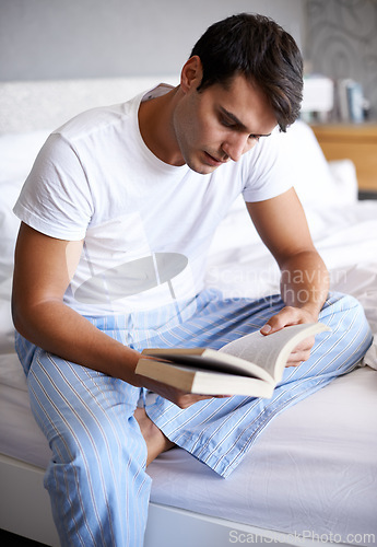 Image of Man, reading and pajamas for book, routine and morning in bedroom for wellness and literature for class. Male person, hobby and student for relaxation, leisure and novel for home free time in house