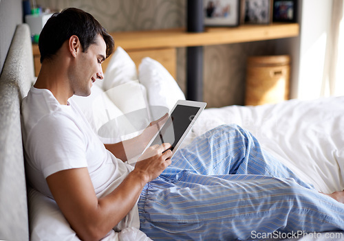 Image of Man, smile and bed with tablet for communication, internet and technology in bedroom, home and apartment in morning time. Male person, student and digital pad on social media, browsing and online