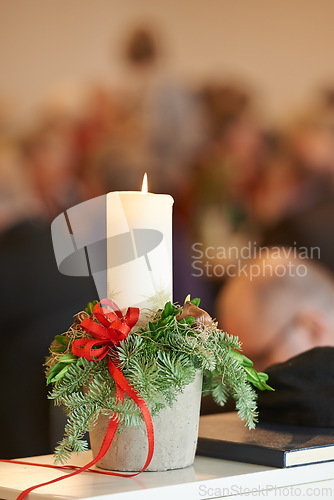 Image of Christmas, religion and candle with mistletoe in church, bible and holy book or gospel on table for worship to God. Spiritual, faith and closeup of wax light to help Christian to pray for heaven