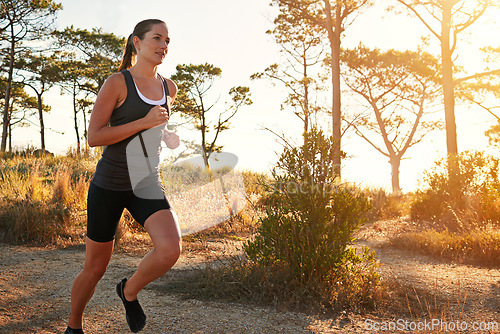 Image of Fitness, running and woman on path in nature for health, wellness and strong body development. Workout, exercise and girl runner on road in woods for marathon training, performance and challenge.