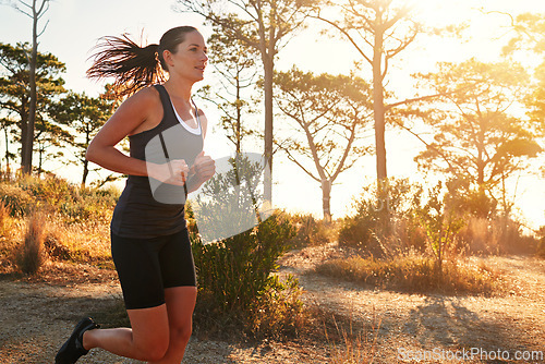 Image of Fitness, running and woman in nature at sunrise for health, wellness and strong body development. Workout, exercise and girl runner on path in woods for marathon training, performance and challenge.