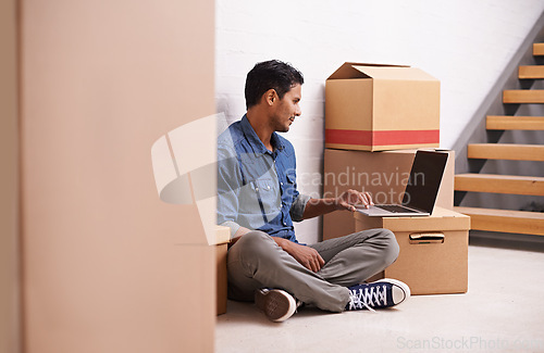 Image of Man, laptop and boxes in new house, apartment and property for moving, relocating and buying a home. Male person, real estate and mortgage for homeowner with computer, communication or technology