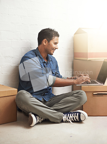 Image of Man, boxes and laptop working in new home, house and residence for moving, relocating or buying property. Male person, real estate or mortgage for homeowner with computer, communication or technology