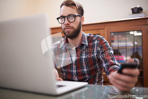 Image of Man, laptop and phone for planning, eyewear and typing or check email for communication. Male person, remote work and notification in home office, reflection and freelancer on internet or app and web