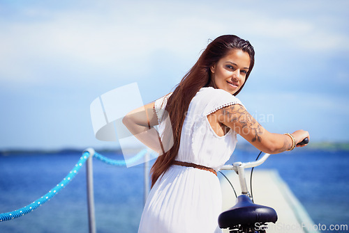 Image of Woman, portrait and sea on pier with bike for adventure, smile or transport on vacation in sunshine. Girl, person and bicycle by waves, ocean or water by bridge, promenade or dock on holiday in Italy