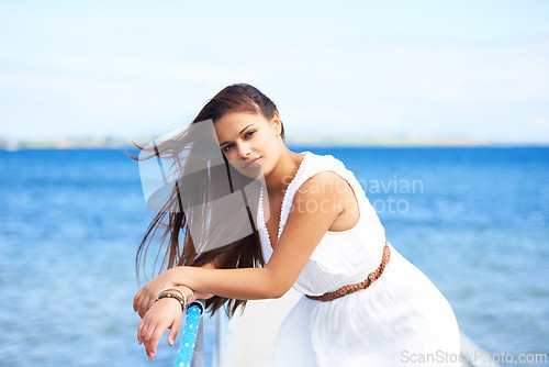 Image of Woman, portrait and ocean on pier in summer with fashion, dress or confidence on vacation in sunshine. Girl, person and outdoor by waves, sea or water by bridge, promenade or dock on holiday in Italy