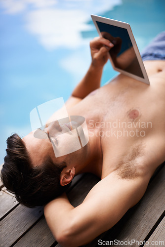 Image of Man, tablet and relax by swimming pool on internet for summer holiday or serious outdoor. Water, digital technology and person on vacation on social media app, networking or reading website on screen
