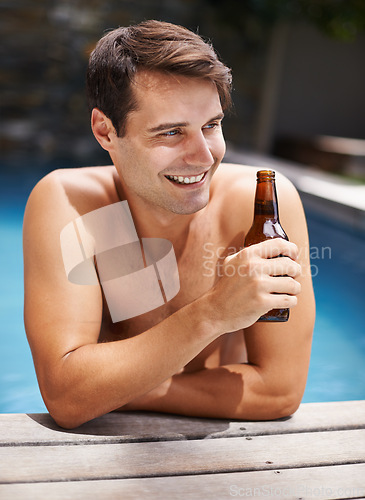 Image of Man, relax and smile in swimming pool with beer to drink or chill on summer vacation, luxury and resort or villa. Male person, bottle and alcohol for refreshments on tropical holiday in Maldives.