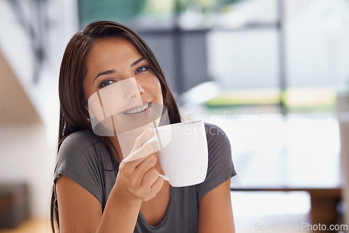 Image of Portrait, coffee and relax with woman in kitchen of home to relax in morning or on weekend time off. Face, smile and mug with happy young person drinking tea in apartment for peace or wellness