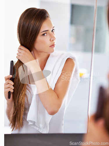 Image of Mirror, woman and brush hair in home bathroom for beauty, care or morning routine with cosmetics. Reflection, hairstyle and serious person combing for cleaning, hygiene and treatment for wellness