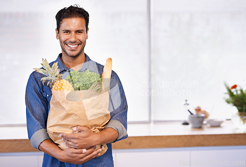 Image of Groceries, bag and portrait of man with healthy food in kitchen for nutrition, diet or cooking in home. Happy, customer and vegan person with a smile for fruits, vegetables and fresh bread in house