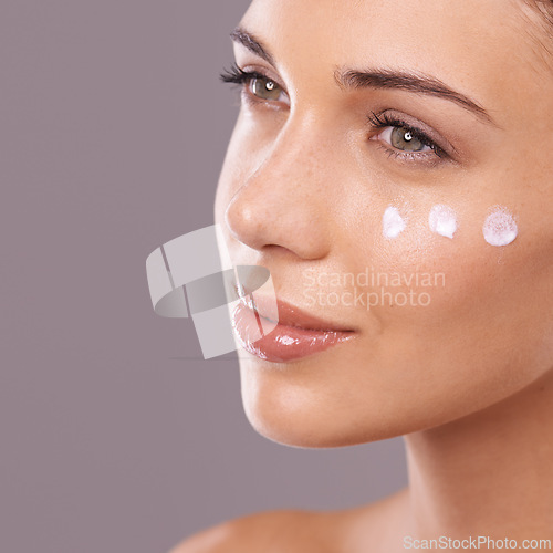 Image of Face, cream and thinking of skincare with woman in studio, moisturizer and dermatology for wellness on purple background. Skin health, cosmetic product with sunscreen or lotion dots, facial or mask