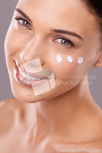 Image of Portrait, cream and woman with skincare, cosmetics and dermatology on grey studio background. Face, person and model with lotion and shine with wellness and beauty with moisturise, smile or aesthetic