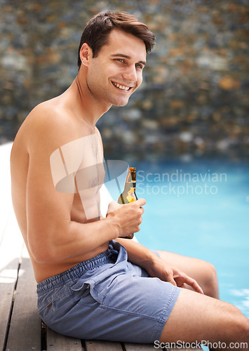 Image of Man, enjoy and happy by swimming pool with beer to relax or chill on summer vacation, luxury and resort or villa. Male person, bottle and alcohol for refreshments on tropical holiday in Maldives.