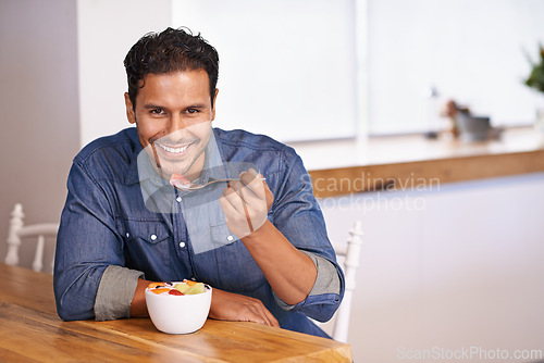 Image of Portrait, smile and man eating fruit salad in home at table for healthy diet, nutrition or wellness at breakfast in the morning. Face, happy person and hungry for food, yogurt or organic strawberry