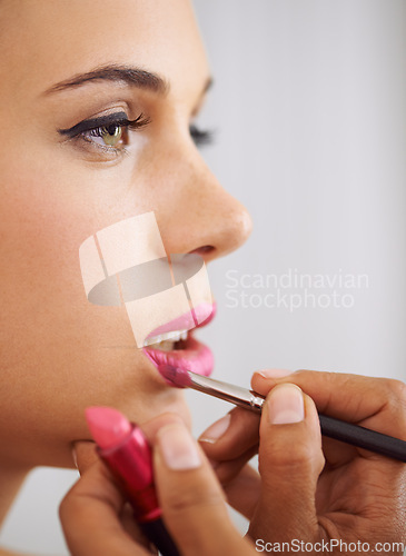 Image of Pretty pink pout. Cropped shot of a beautiful woman having lipstick applied with a makeup brush.