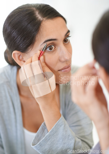 Image of Face, cosmetics and tweezer with eyebrows of woman in mirror of home bathroom for grooming or hygiene. Beauty, cleaning or wellness with young person in apartment for morning hair removal routine