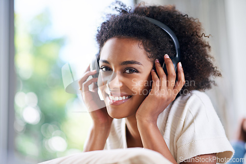 Image of Headphones, smile and portrait of woman at her home listening to podcast, music or radio. Happy, relax and young female person streaming song, playlist or album with technology in living room.