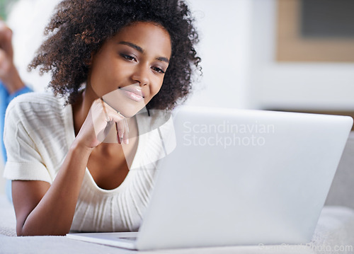 Image of Reading, laptop and woman on sofa working on freelance creative project in living room. Relax, technology and young African female designer typing on computer for research on couch in apartment.